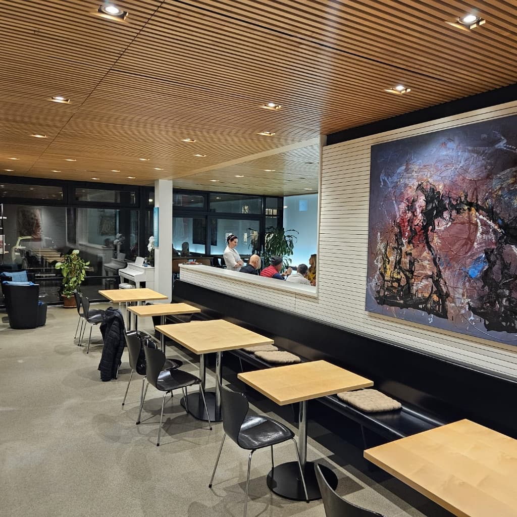 Innenraum des ArtCafé Megg in Meggen mit Holzdecke und Kunst an der Wand